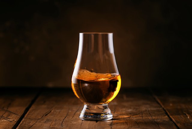 Scotch Whiskey without ice in glass, rustic wood background, cop